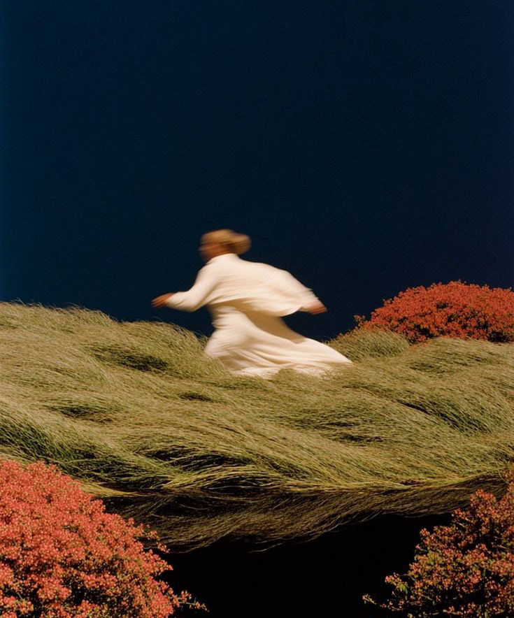 Woman in white running through a windswept field
